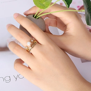 Bague couronne dorée élégante avec perle et cristaux portée à la main d'un mannequin