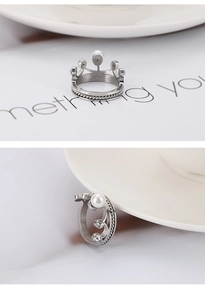 Détails macro d'une bague couronne argentée avec perle, zircons et texture tressée