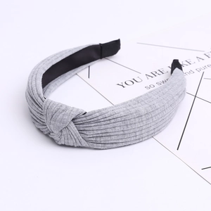 Close-up of light grey knitted cotton headband with knot detail and ribbed fabric texture