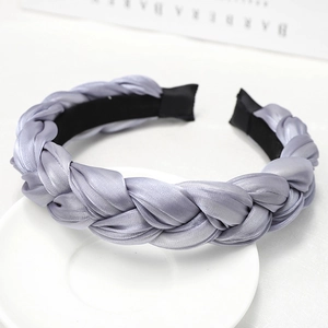 Detailed view of a silver-grey braided silk headband on a white ceramic plate