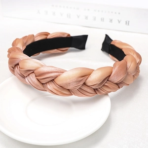 Detail of champagne braided headband with silk texture on white tray with book