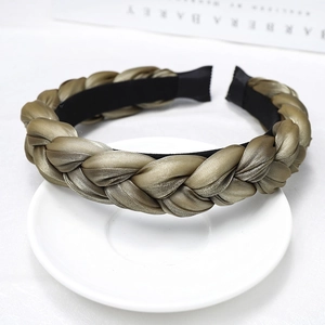 Macro shot of olive green braided satin headband with metallic sheen on white ceramic tray
