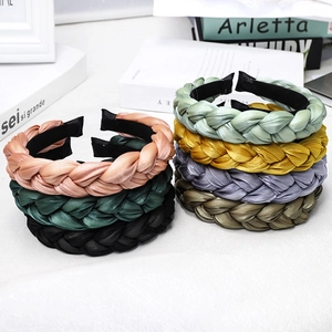 Detailed pile of multi-color braided silk headbands on a white table with decorative props