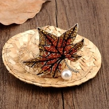 Macro detail of maple leaf brooch with amber crystals and a single white pearl