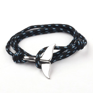 Braided rope nautical bracelet with silver whale tail anchor charm on white background