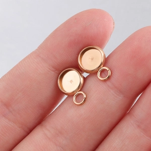 Macro shot of two rose gold stainless steel earring studs with loops on a fingertip