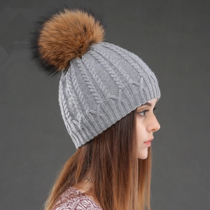 Winter knitted beanie with raccoon fur pompom in grey cable knit pattern for women