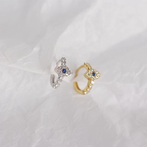 Macro shot of silver and gold evil eye hoop earrings with blue stones and crystals