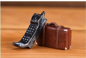 Macro shot of miniature vintage resin mobile phone and brown suitcase decor props