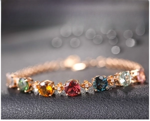 Dettaglio del bracciale con pietre preziose multicolore e maglie floreali in oro rosa