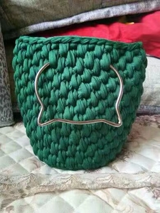 Detail view of dark green hand-knitted bucket bag with silver cat-shaped metal handle