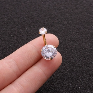 Close-up of a gold belly button ring with two clear round zircons held by fingers