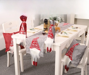 Chemin de table de Noël et housses de bouteille de vin dans un décor de salle à manger