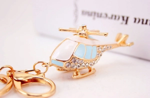 Macro shot of gold helicopter keychain with white body and sparkling rhinestone accents