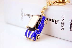 Close-up of blue beetle car keychain with gold finish and sparkling rhinestones