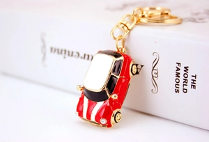 Macro shot of a red metal beetle car keychain with gold ring on a white book