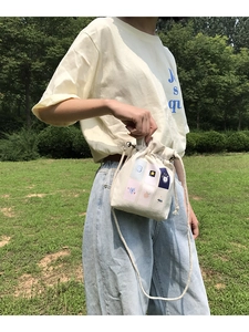 Detailed view of cream canvas bucket bag with floral illustration and cotton rope strap