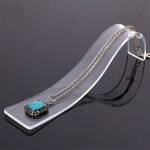 S-shaped acrylic jewelry stand displaying a silver necklace with a green pendant