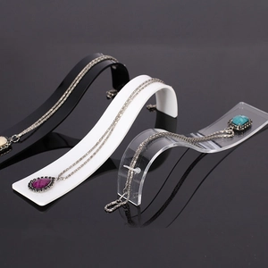 S-shaped acrylic necklace display stand in black, white, and clear on mirror surface