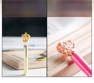 Detail of hollow metal crown and heart pen toppers in gold and rose gold finishes