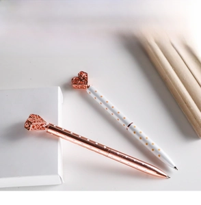 Close-up of metal ballpoint pens with heart-shaped tops in rose gold and polka dot patterns