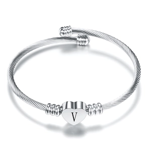 Close-up of silver twisted cable bracelet with a heart charm engraved with letter V