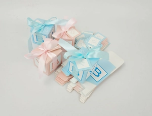 Detail of pink and blue baby party favor boxes with ribbons and for you tags