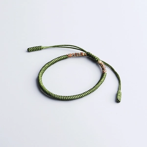 Detail of green handmade woven vajra knot bracelet with multi-color silk accents