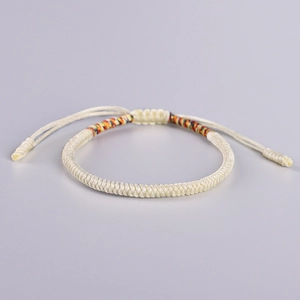 Detailed view of adjustable cream braided bracelet with colorful accents and sliding knot