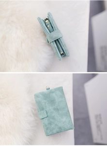 Detail view of a light blue matte suede short wallet with snap button and side zipper