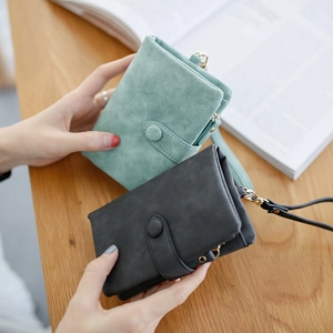 Close-up of green and black matte PU leather wallets with wrist straps on a wooden desk