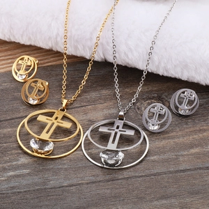Elegant hollow cross necklace and earring set with crystals on a wooden background