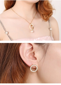 Close-up of model wearing gold circular hollow necklace and earrings set with pearls