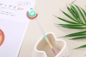 Detail of creative cartoon pens with blue flamingo and rainbow toppers on a desk