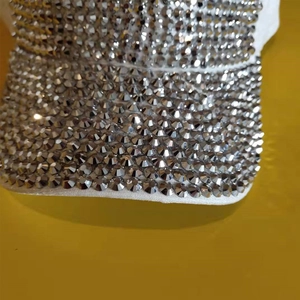 Close-up of sparkling silver rhinestones on a white baseball cap brim detail