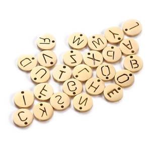 Macro detail of golden stainless steel round letter pendants for DIY jewelry making