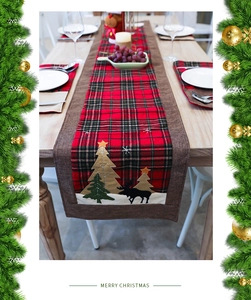Detail of red and black plaid table runner with Christmas tree and elk embroidery