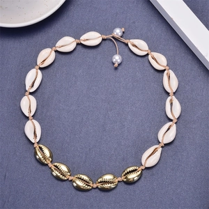 Detail of woven shell necklace with natural white beads, golden accents and pearl charm