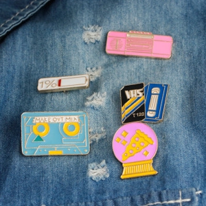 Set of five retro enamel pins featuring a boombox, VHS, and mix tape on blue denim jacket