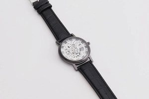 Detailed view of a men's skeleton quartz watch with a black leather strap texture