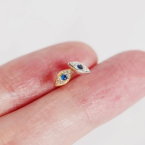 Macro shot of S925 silver devil eye stud earrings with blue gems and white crystals