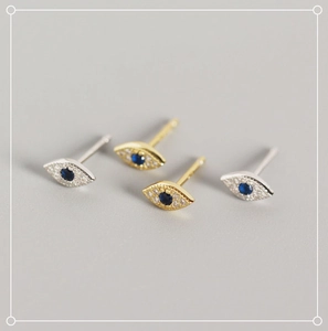 Macro shot of silver and gold S925 sterling silver evil eye stud earrings with blue stones