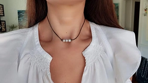 Trois perles sur collier en cuir marron porté par un mannequin pour un look élégant