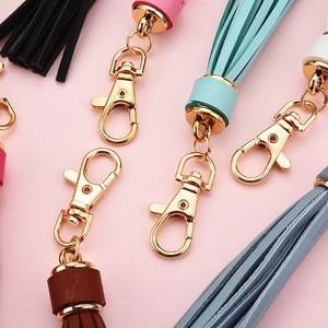 Colorful PU leather tassel keychains with golden metal caps on a pink background