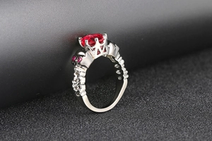 Macro shot of gothic black gold skull ring with a large oval red ruby centerpiece