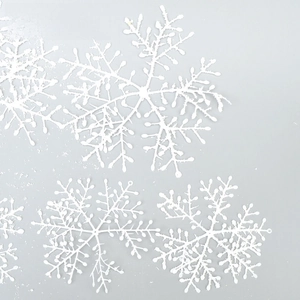 Macro detail of white glittery snowflake ornaments for Christmas tree and window decor