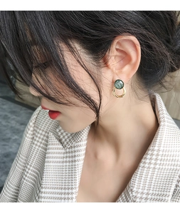Close-up of vintage gold-tone earrings with emerald green marble-textured circular studs