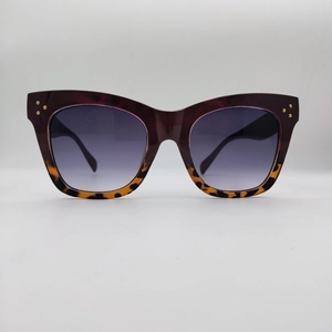 Close-up of oversized tortoiseshell sunglasses with three gold rivets and gradient lenses