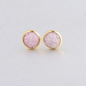 Detail view of 10mm round gold-plated earrings with pink mineral stone inlay