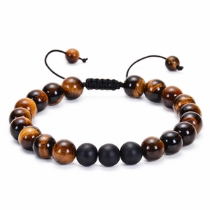 Macro detail of natural red tiger eye and matte black stone beads on woven bracelet